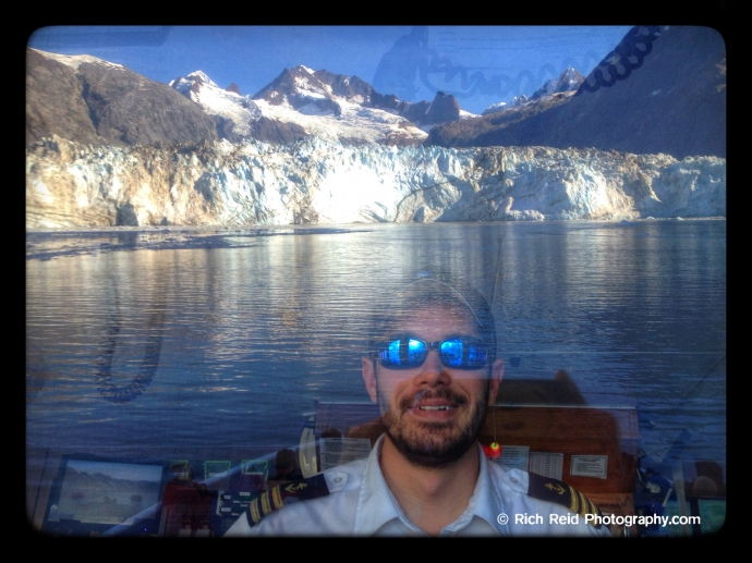 #5 Lindblad Expeditions's Chief Mate at the helm with Johns Hopkins Glacier reflecting in the window in Glacier Bay National Park, Alaska.