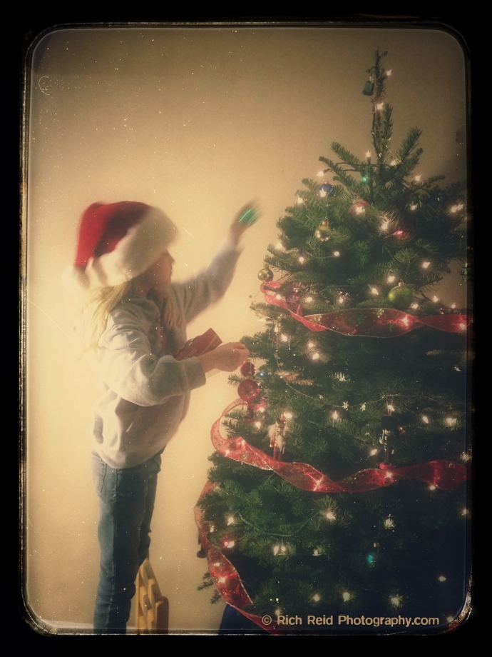 Vintage look of a girl decorating a Christmas tree.